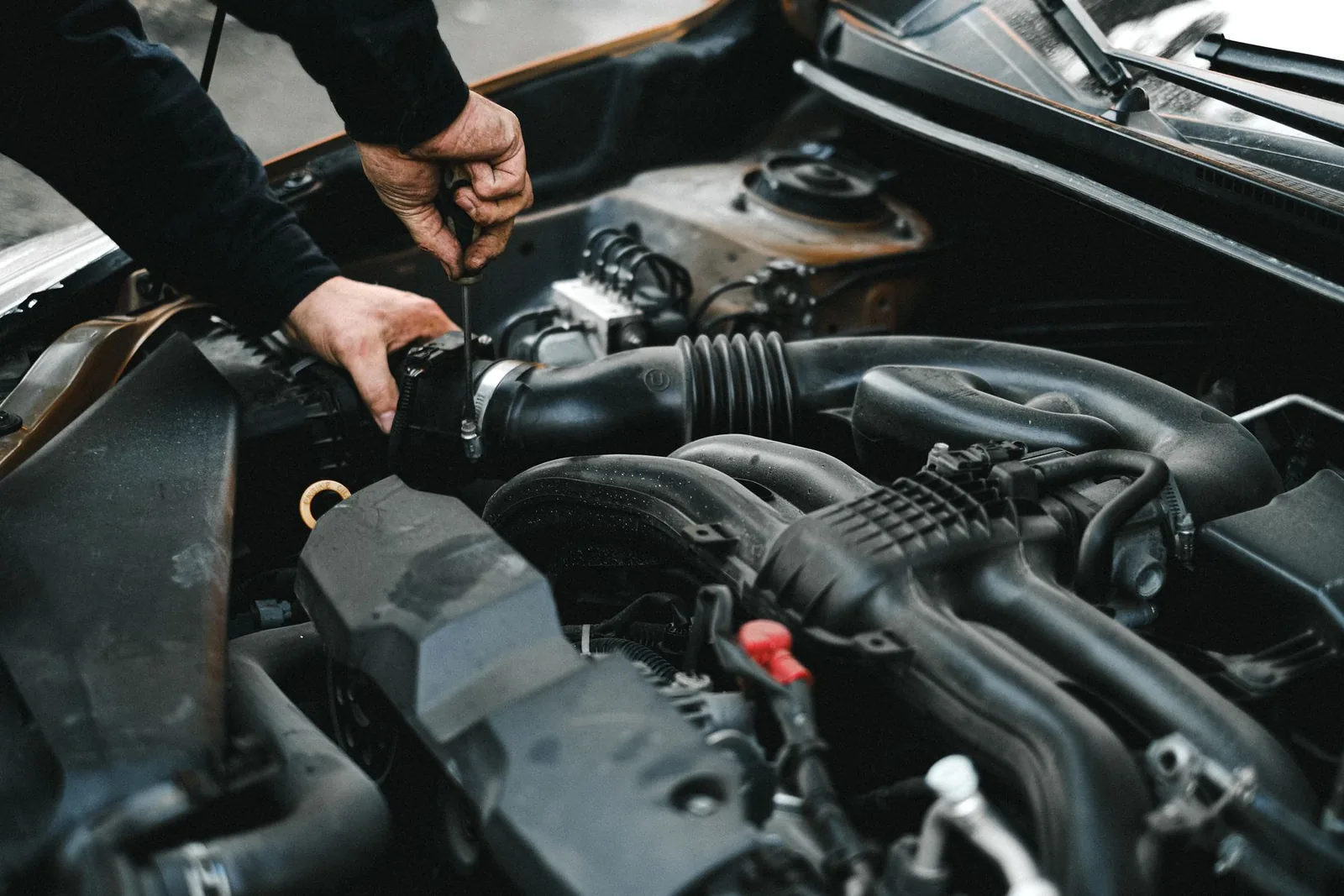 Hands working in an engine bay — illustrative stock photograph